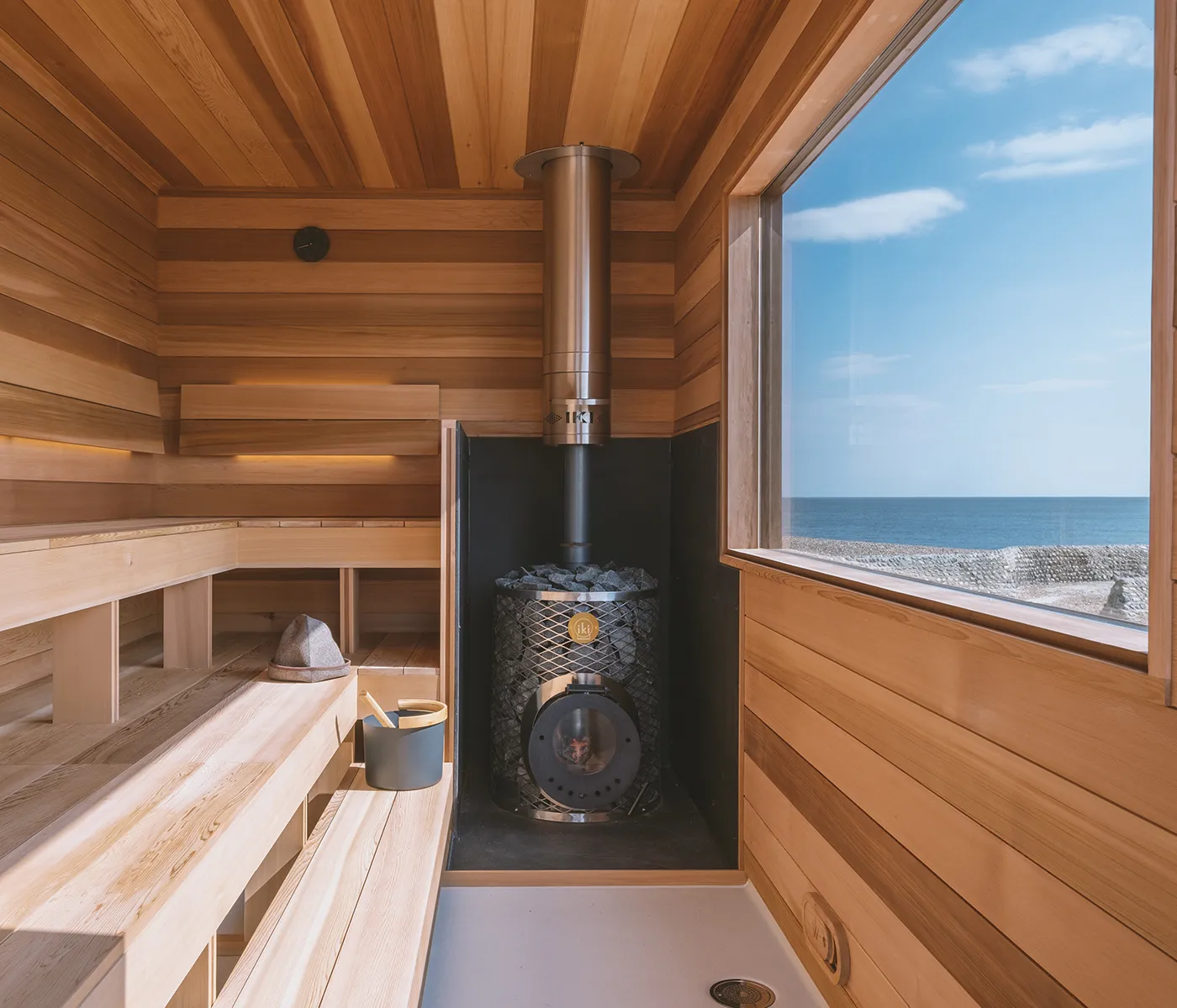 Sauna Interior with Stove and a Sea View Through the Window Traditional Nordic sauna wood heater with cedar interior by Wildhut compared to an infrared sauna panel